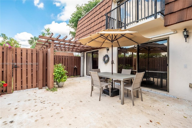 view of patio with fence, outdoor dining space, a balcony, and a pergola