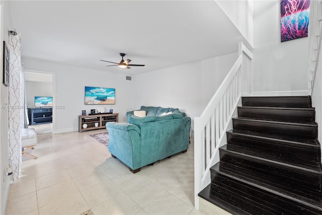 living room featuring visible vents, a ceiling fan, light tile patterned floors, baseboards, and stairs