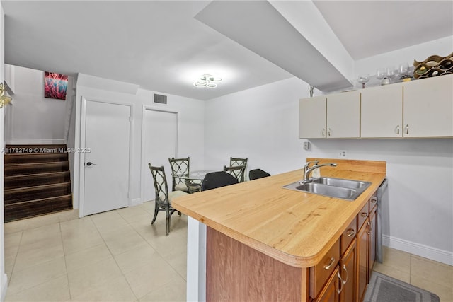 kitchen with baseboards, visible vents, wooden counters, light tile patterned flooring, and a sink