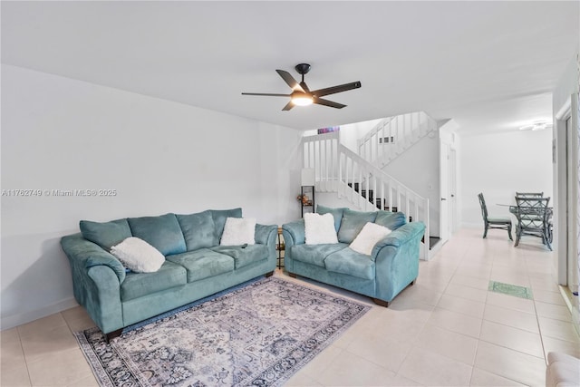 living area with stairway, light tile patterned floors, a ceiling fan, and baseboards