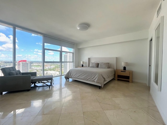 bedroom featuring a city view, baseboards, a wall of windows, and visible vents