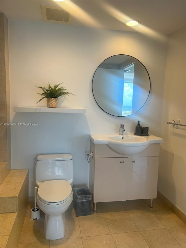 bathroom with vanity, baseboards, visible vents, tile patterned flooring, and toilet