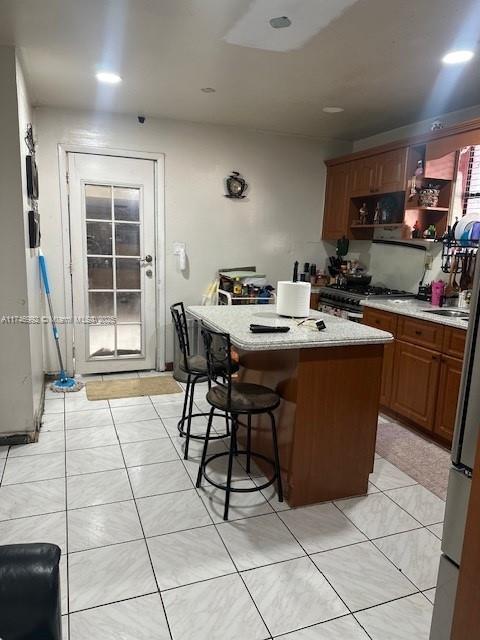 kitchen featuring range with gas cooktop, a breakfast bar, light tile patterned floors, and a kitchen island