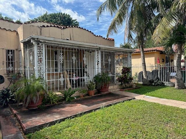 2162 NW 26th St, Miami, FL 33142 - view of front of home featuring a tile roof, a front lawn, and fence