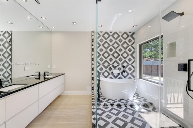 bathroom with a soaking tub, recessed lighting, double vanity, and a sink