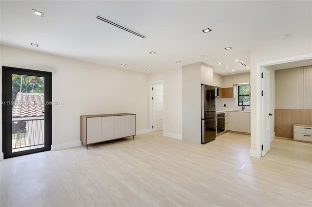 unfurnished living room featuring baseboards, visible vents, recessed lighting, a sink, and light wood-type flooring