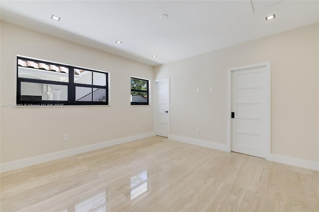 empty room with recessed lighting, baseboards, light wood-style floors, and attic access