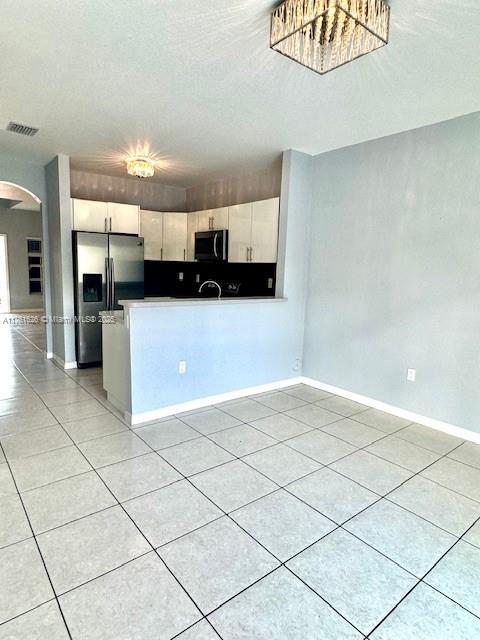 kitchen featuring visible vents, arched walkways, white cabinets, and stainless steel fridge with ice dispenser