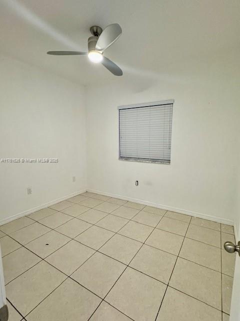 unfurnished room featuring light tile patterned flooring, baseboards, and a ceiling fan