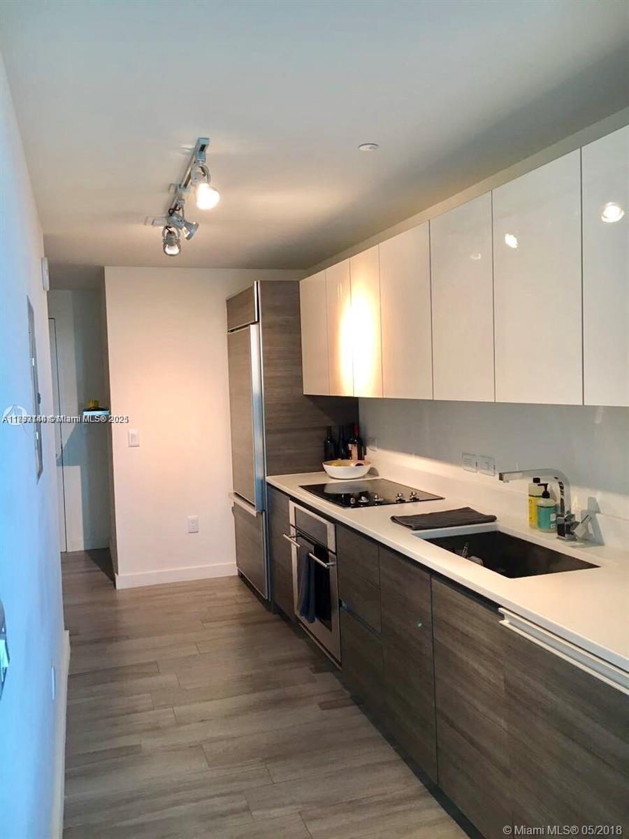 kitchen with a sink, stainless steel appliances, light countertops, white cabinets, and modern cabinets