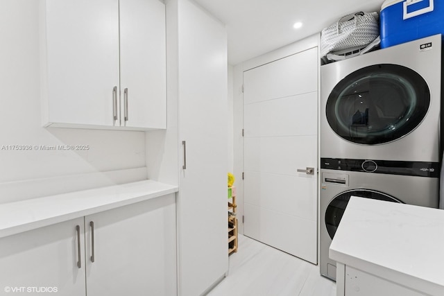 clothes washing area with recessed lighting, stacked washer / dryer, and cabinet space