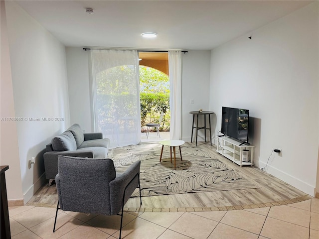 tiled living area featuring a wall of windows and baseboards