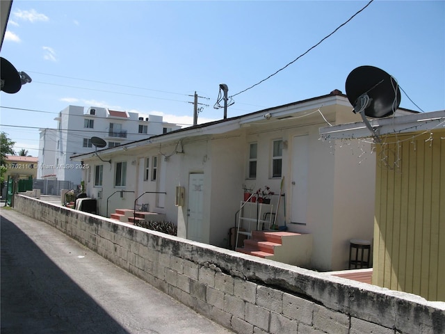 back of house with entry steps and stucco siding