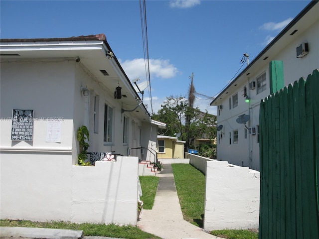 view of side of home featuring fence and stucco siding