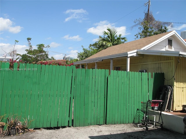 view of side of home featuring fence and a shingled roof