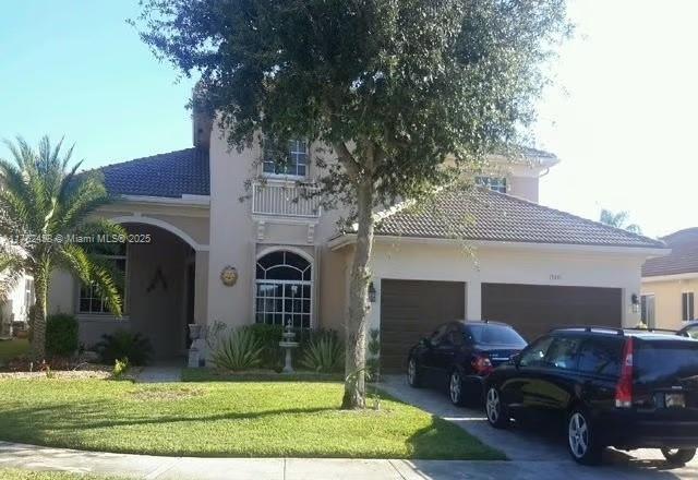 view of front of property featuring stucco siding, concrete driveway, a front lawn, and a tile roof