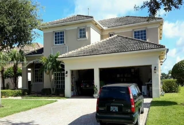 exterior space with a tile roof, a garage, driveway, and stucco siding