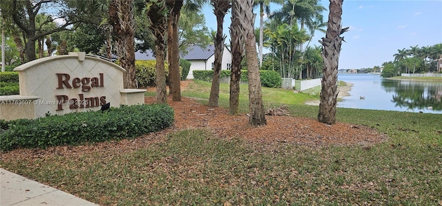 community sign featuring a lawn and a water view