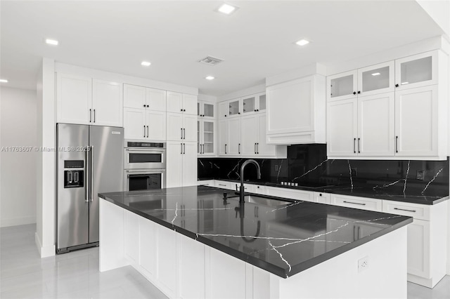 kitchen featuring visible vents, a sink, stainless steel appliances, white cabinetry, and backsplash