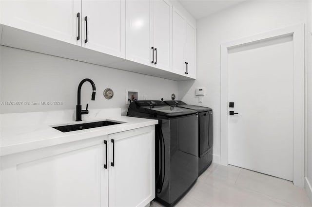 laundry area featuring separate washer and dryer, light tile patterned floors, cabinet space, and a sink