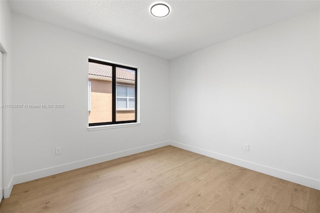 empty room featuring light wood-type flooring and baseboards