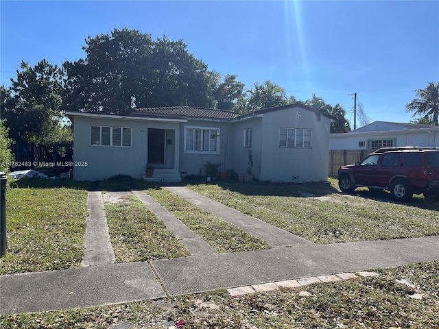 view of front of house with concrete driveway, fence, a front lawn, and stucco siding