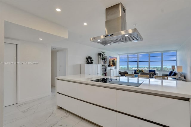 kitchen with marble finish floor, white cabinetry, island range hood, light countertops, and black electric stovetop