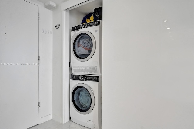 laundry area with laundry area, stacked washer / dryer, and marble finish floor