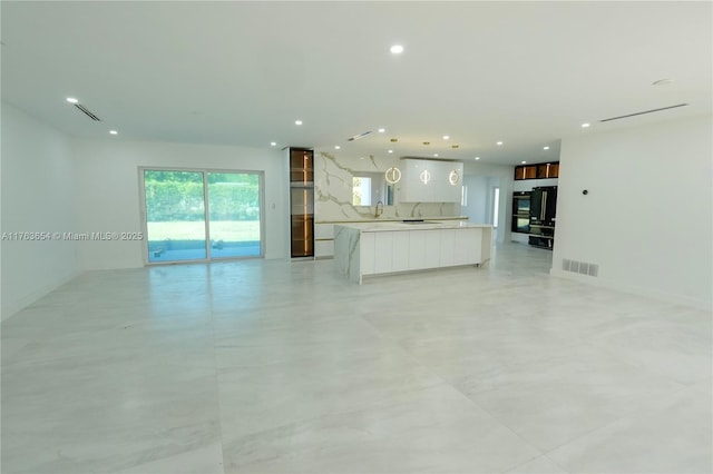 unfurnished living room featuring visible vents, recessed lighting, and a sink