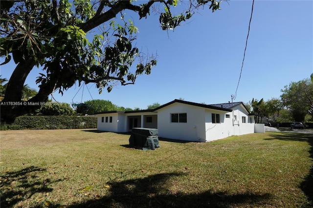 rear view of property with a standing seam roof, a lawn, and stucco siding