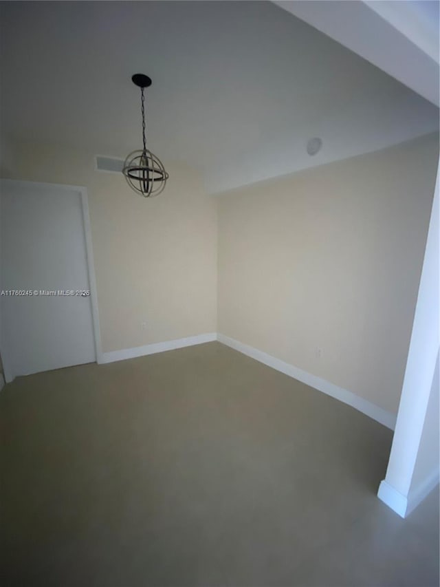 spare room with a chandelier, finished concrete flooring, and baseboards