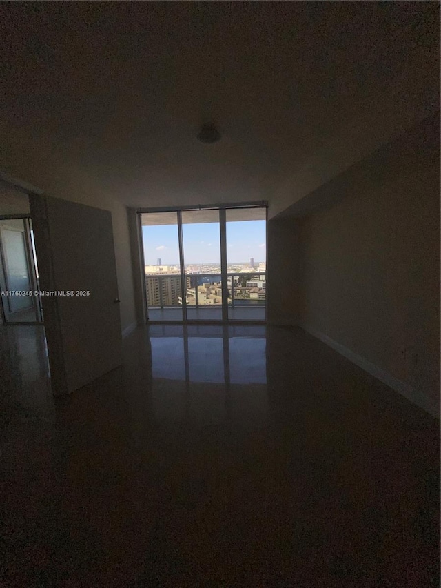 unfurnished room with floor to ceiling windows and speckled floor