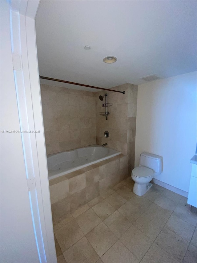 bathroom with tile patterned flooring, toilet, baseboards, and tiled shower / bath combo