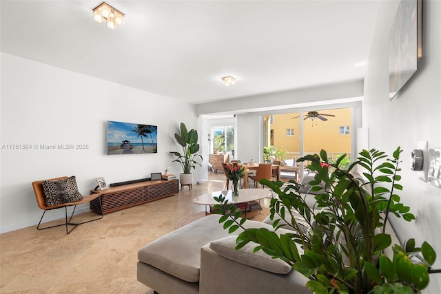 living area with baseboards and a ceiling fan