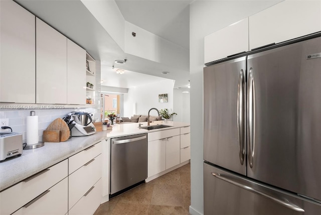 kitchen featuring a sink, stainless steel appliances, light countertops, white cabinetry, and backsplash