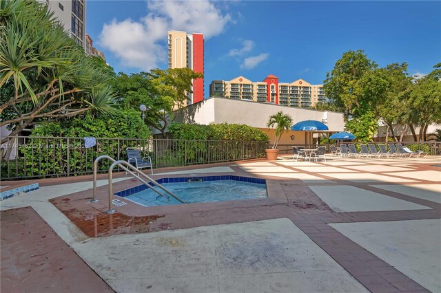 view of pool with a patio, fence, and a hot tub