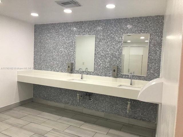 bathroom with tile walls, visible vents, and a sink