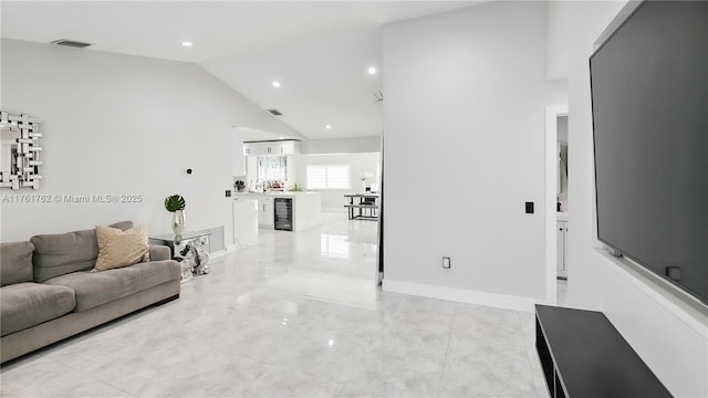 living area with visible vents, baseboards, high vaulted ceiling, and beverage cooler