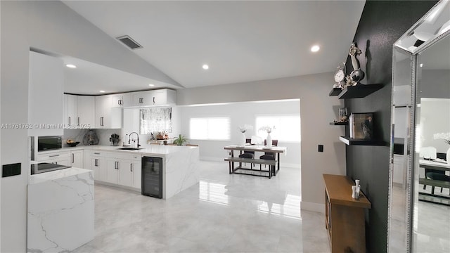 kitchen featuring visible vents, black appliances, beverage cooler, white cabinetry, and light stone countertops