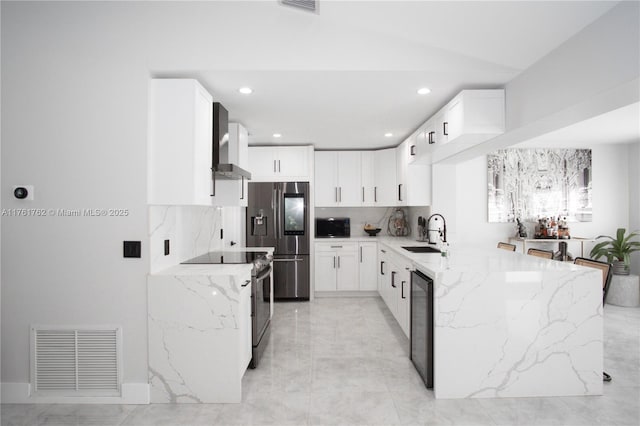 kitchen with light stone countertops, visible vents, a sink, stainless steel appliances, and wall chimney exhaust hood