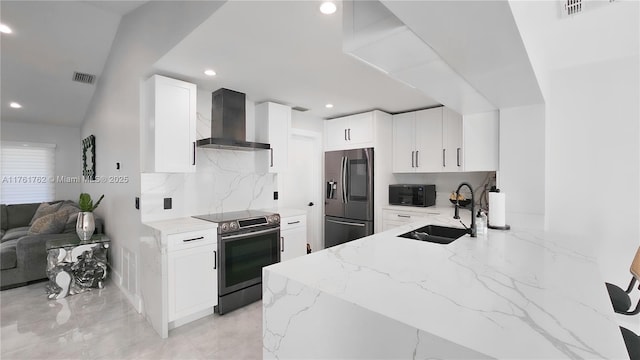 kitchen featuring a sink, stainless steel appliances, wall chimney exhaust hood, decorative backsplash, and light stone countertops