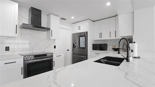 kitchen featuring visible vents, light stone countertops, stainless steel appliances, wall chimney exhaust hood, and a sink