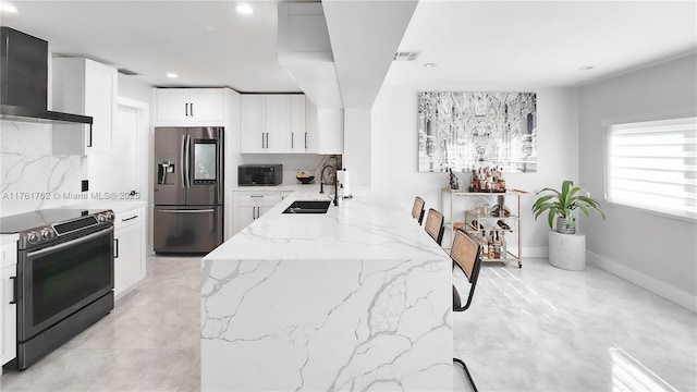 kitchen featuring light stone counters, visible vents, a sink, appliances with stainless steel finishes, and wall chimney range hood