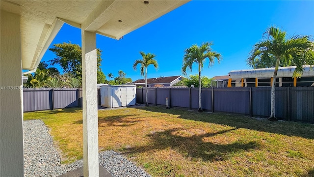 view of yard with an outdoor structure, a fenced backyard, and a shed