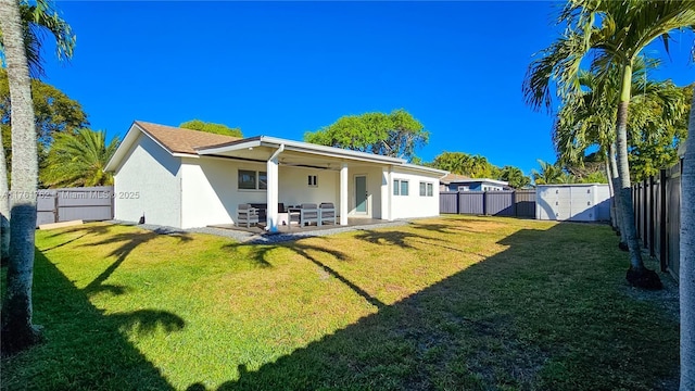 back of property with stucco siding, a lawn, a fenced backyard, and a patio area