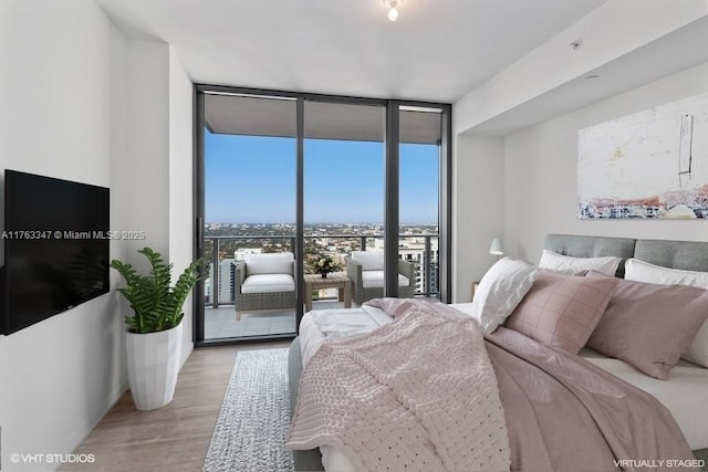 bedroom featuring a wall of windows and light wood finished floors