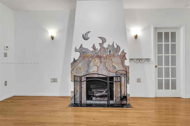 room details featuring baseboards, wood finished floors, and a fireplace