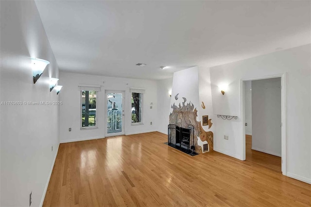 unfurnished living room featuring visible vents, baseboards, a fireplace, and light wood finished floors