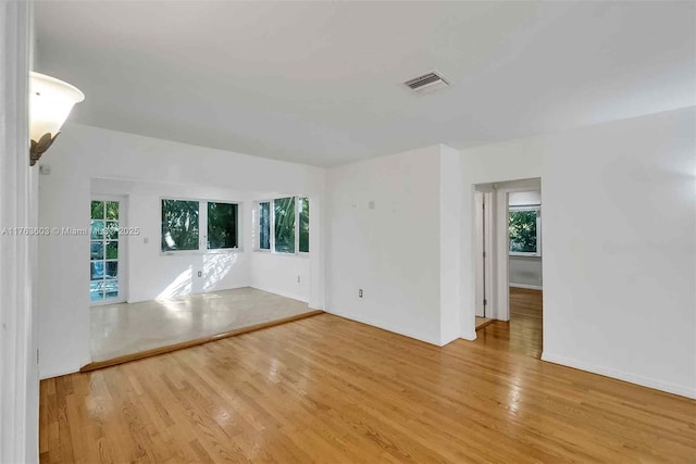 unfurnished room with light wood finished floors, visible vents, and a healthy amount of sunlight