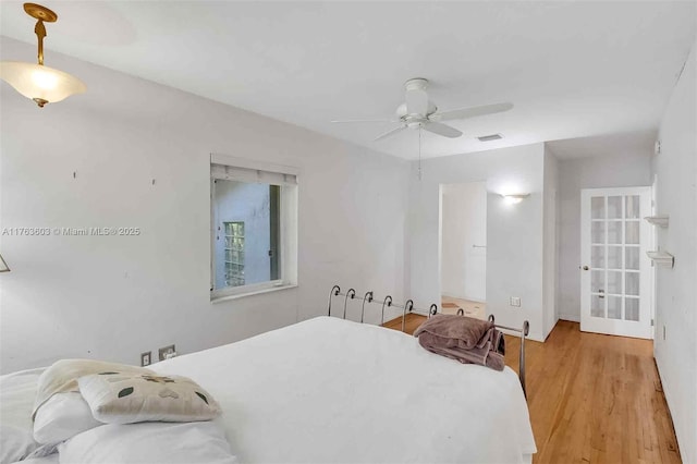 bedroom with visible vents, french doors, a ceiling fan, and wood finished floors